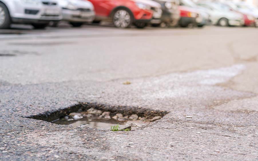 A pothole in a poorly maintained commercial parking lot