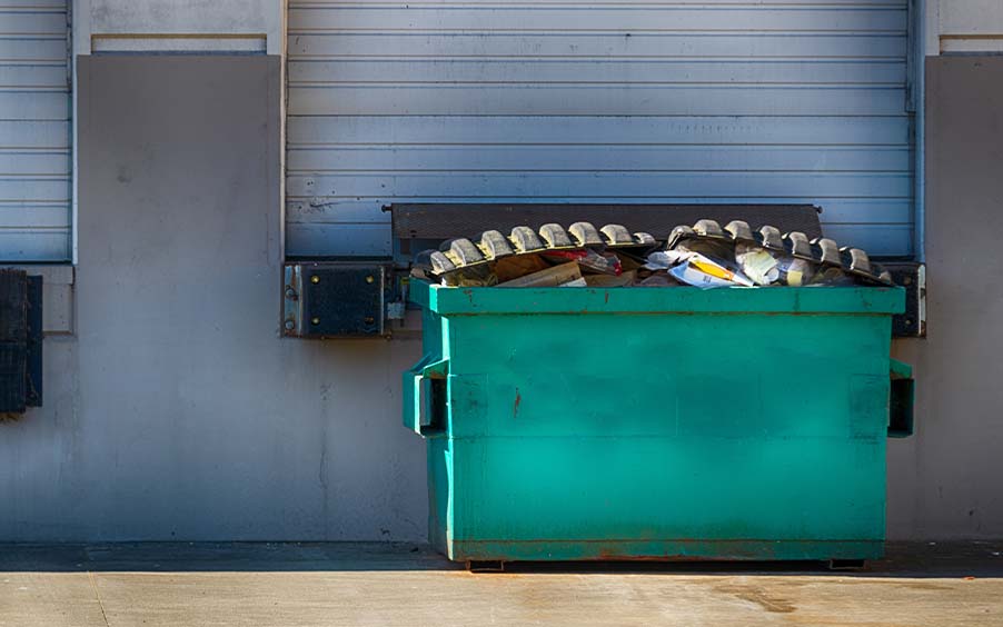 A dumpster outside a commercial building loading dock