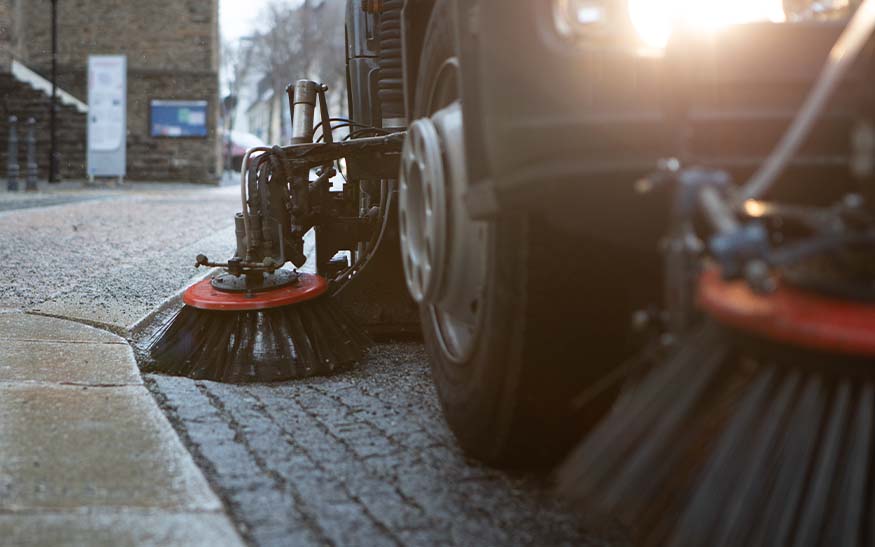 Sweeper truck cleaning a cobblestone parking area
